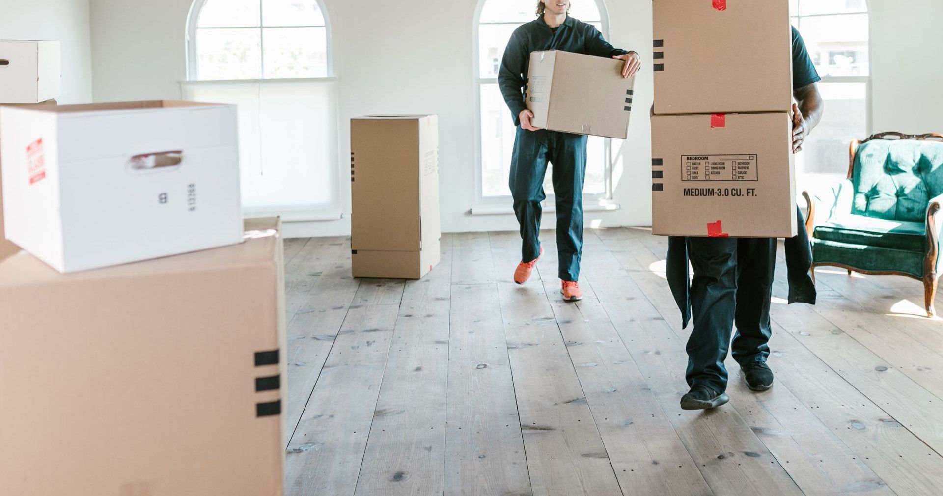 Two movers carrying boxes in a sunlit room, ready to assist with relocation.